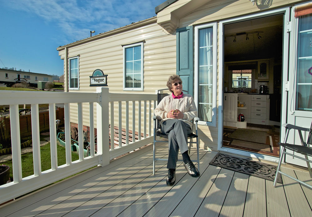 A woman enjoying sitting on her decking in her residential park home at Courthill